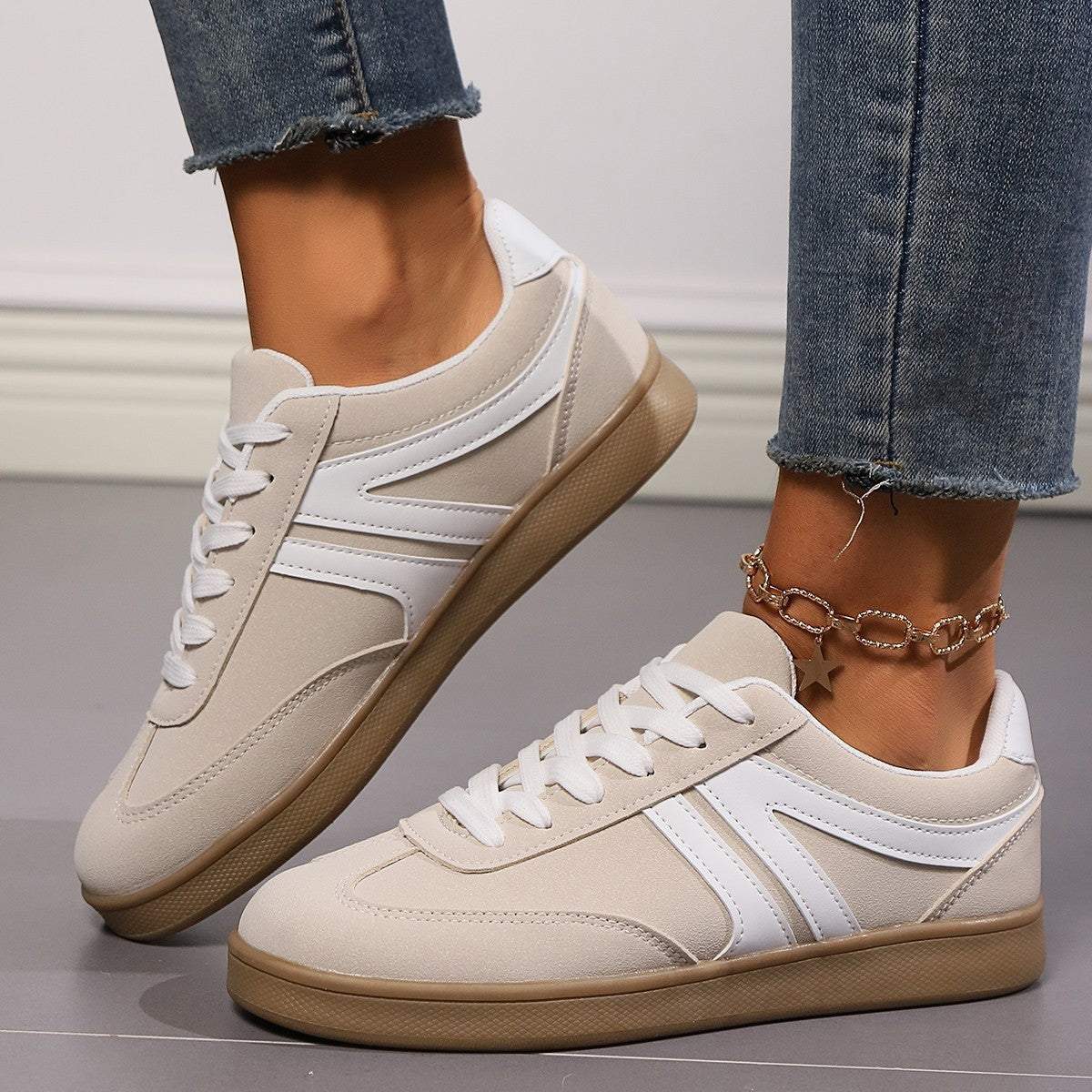 Beige and white lace-up round toe flats shoes with rubber sole worn with blue jeans