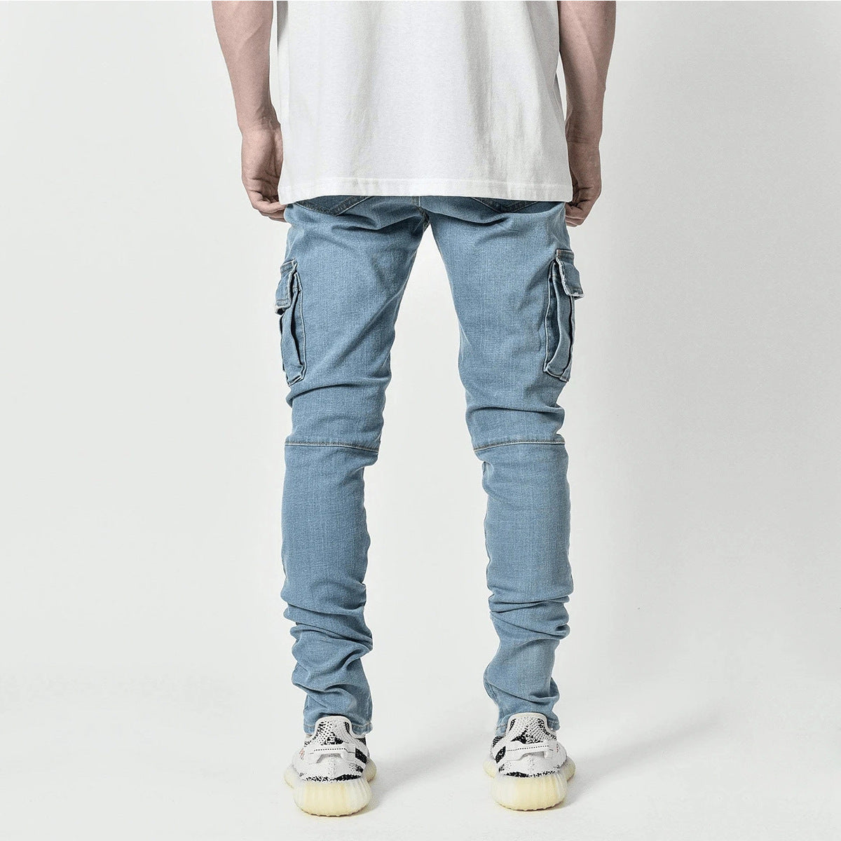 Back view of men's light blue denim multi-pocket tooling jeans with middle waist and zipper placket
