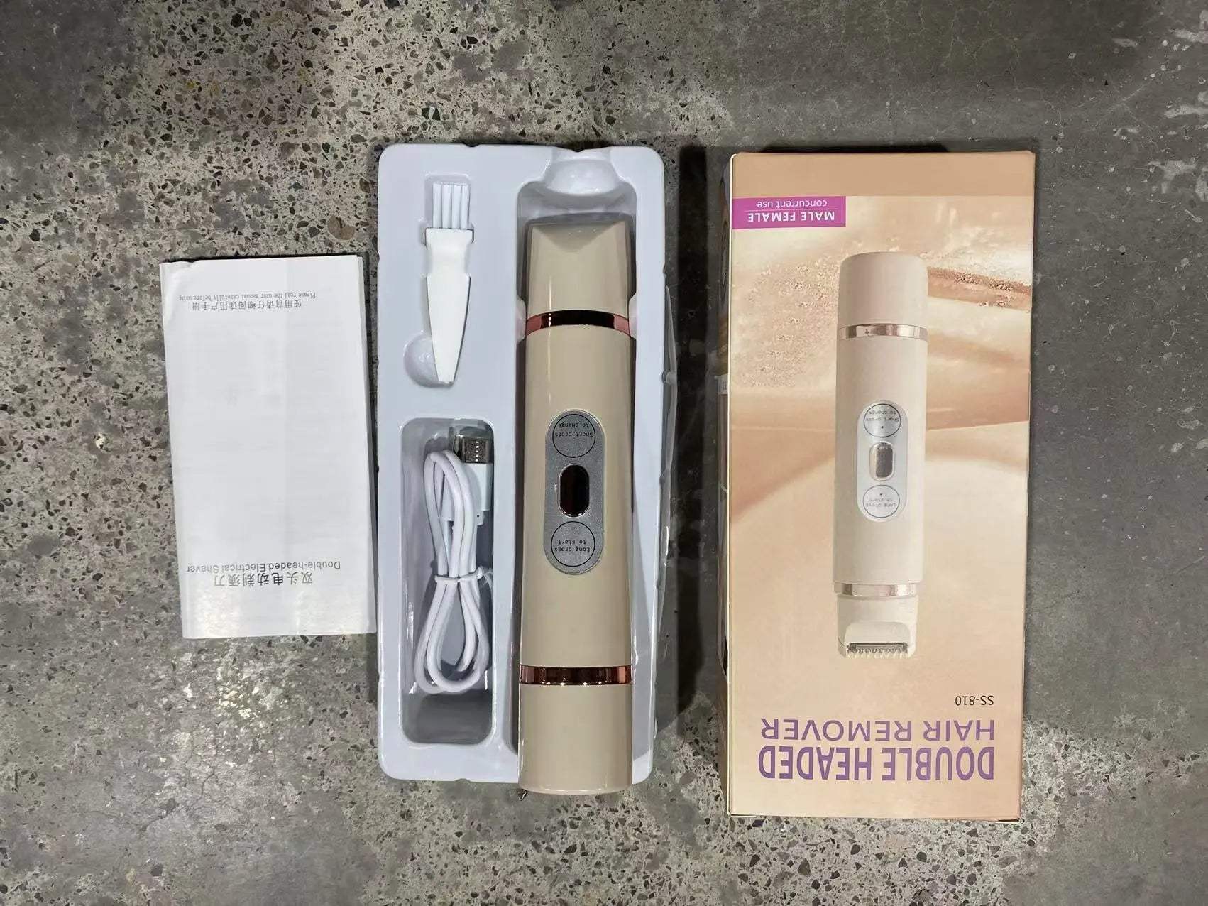 USB rechargeable dual-head electric shaver for women with cleaning brush and beige body in packaging box on concrete surface