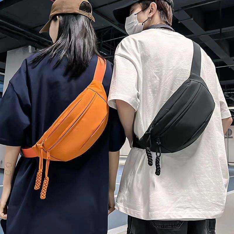 Men wearing orange and black crossbody chest bags in casual urban style