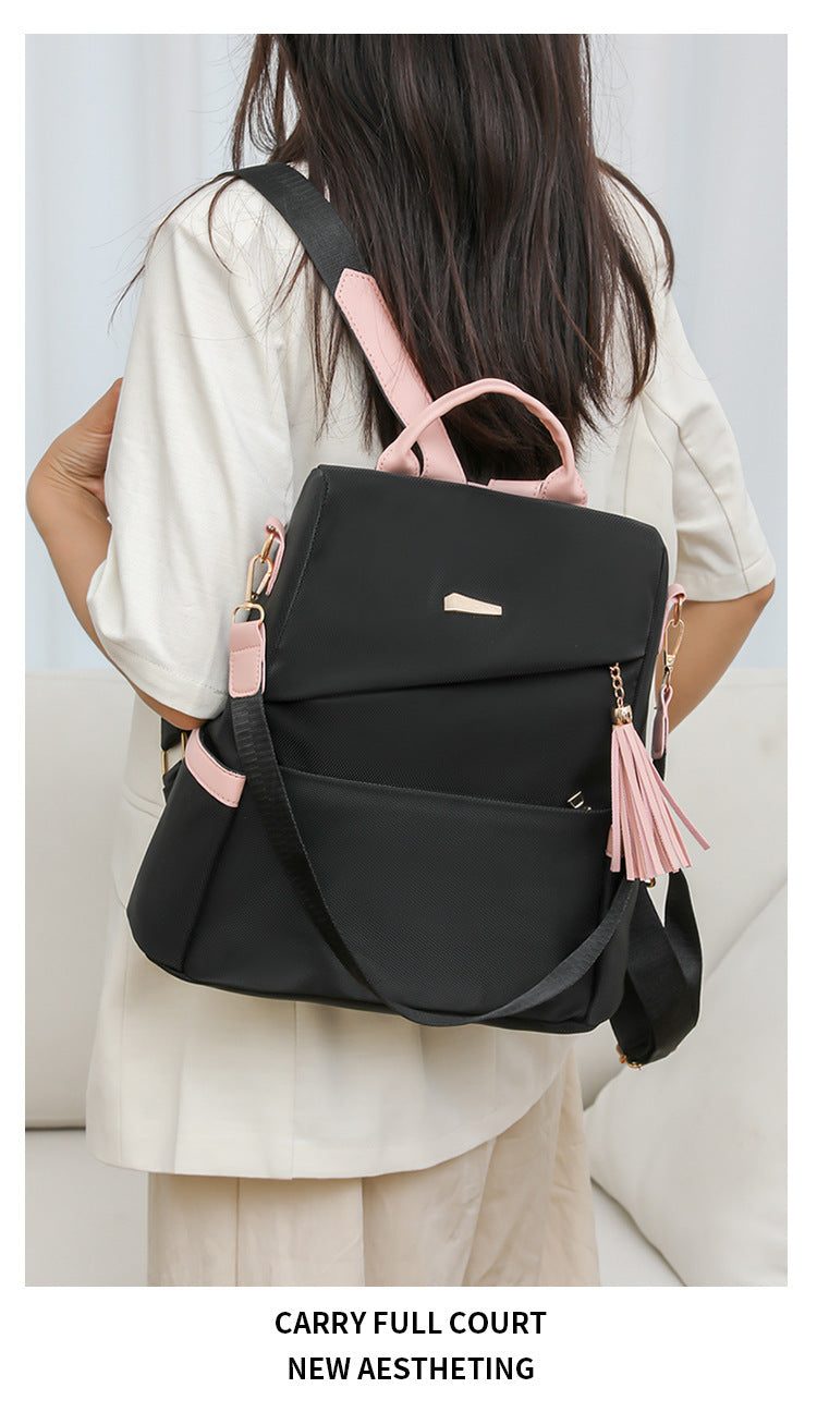 Oxford cloth stitching women's black backpack with pink accents and tassel detail, anti-theft design, suitable for school and casual travel.
