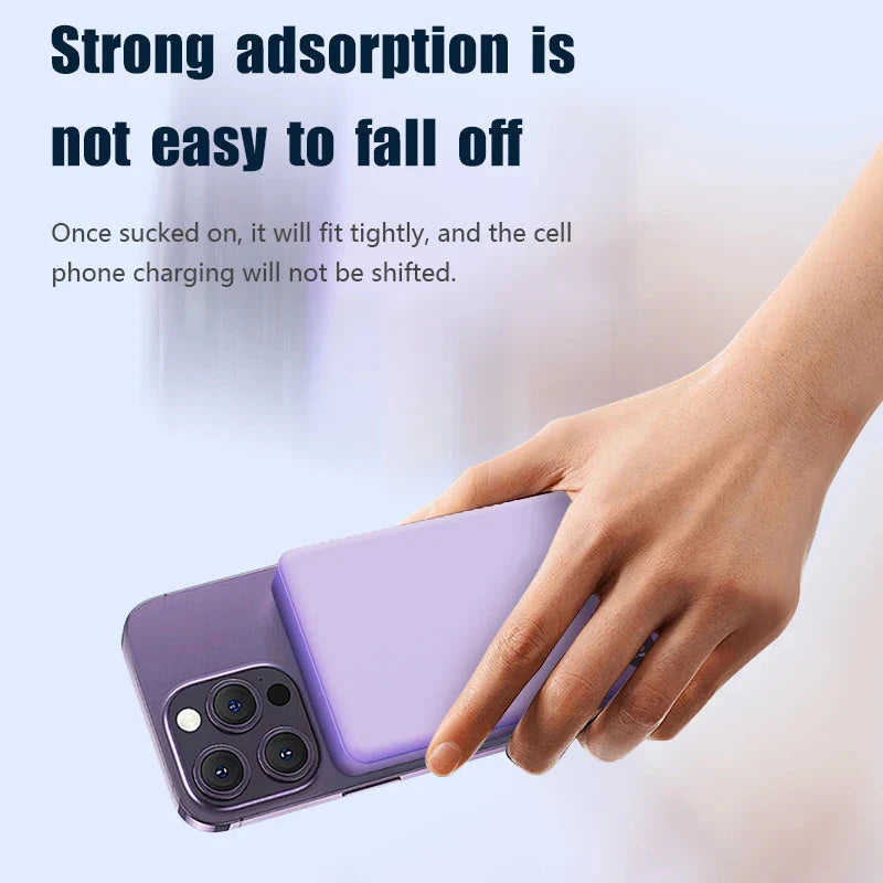 Hand holding purple magnetic power bank attached to purple smartphone for wireless charging