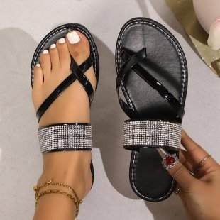 Black toe covering rhinestones strap flat bottom beach sandals on foot and held in hand