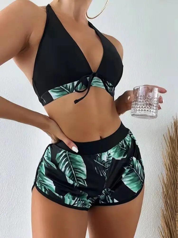 Woman wearing black leaf print bikini top with matching shorts holding glass cup