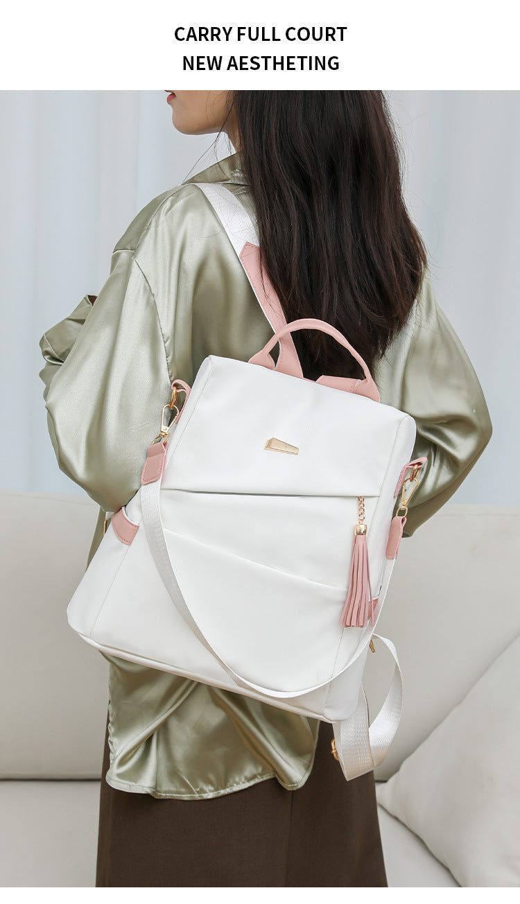 Oxford cloth stitching women's backpack in white with pink accents, anti-theft back zipper, casual travel and schoolbag design, medium hardness, PU material.
