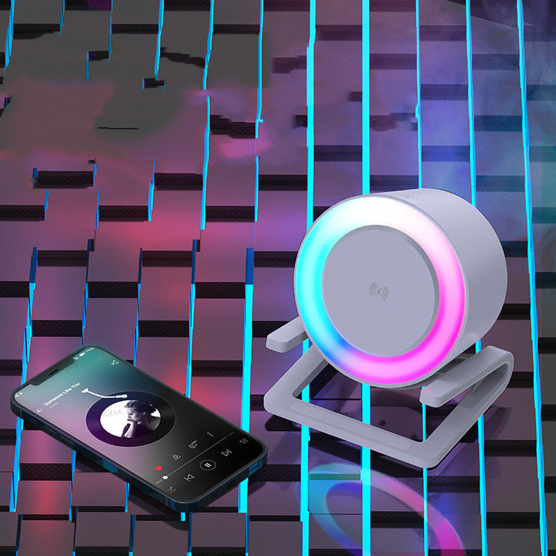 White Bluetooth speaker with colorful LED ring and wireless charging next to smartphone on futuristic surface