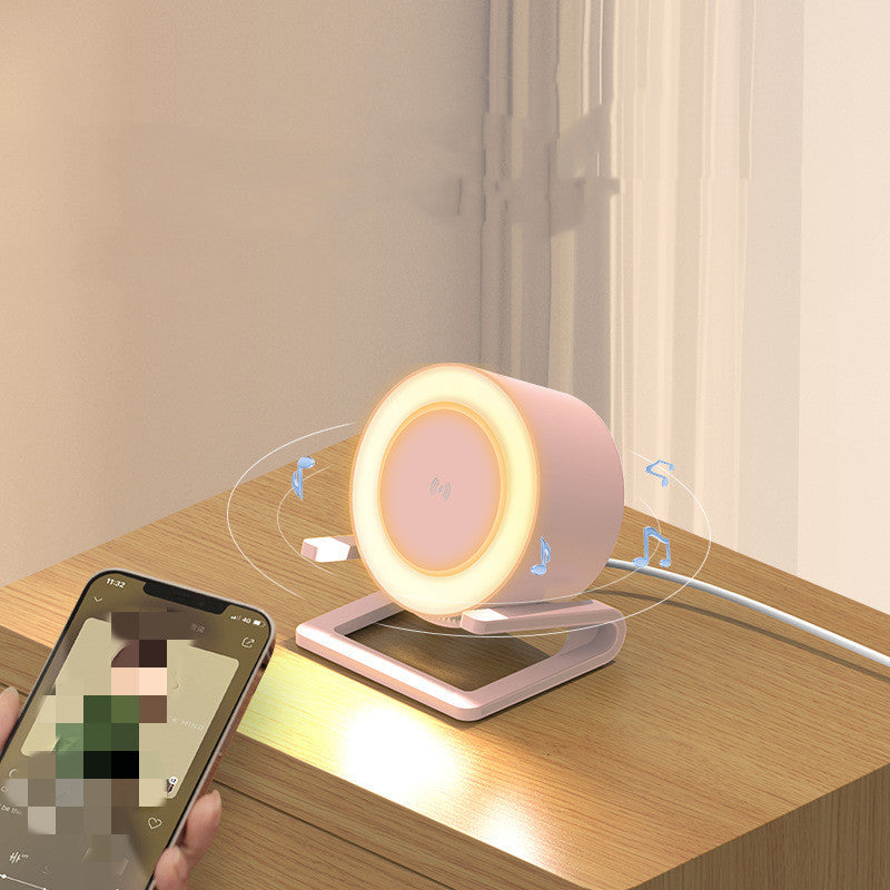 White Bluetooth speaker with wireless charging on wooden desk next to smartphone playing music